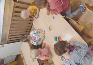 Dzieci siedzą przy stole i lepią z plasteliny